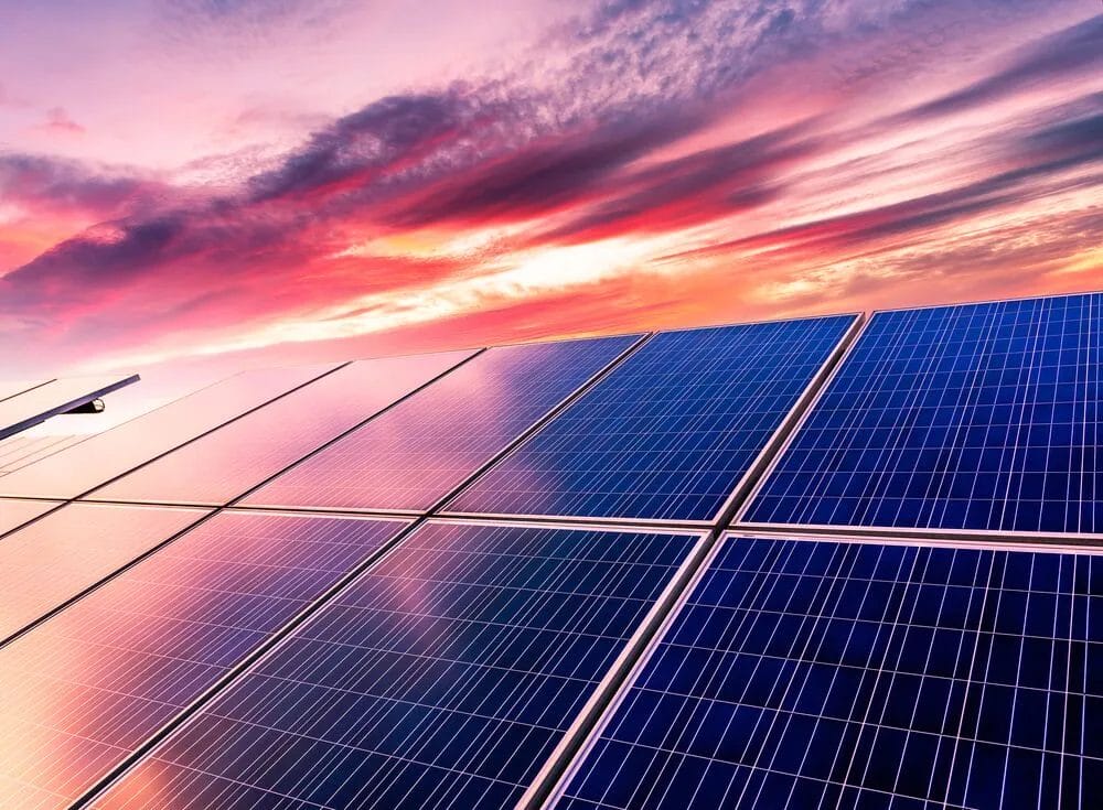 Solar panels reflecting a vibrant sunset sky, showcasing renewable energy.