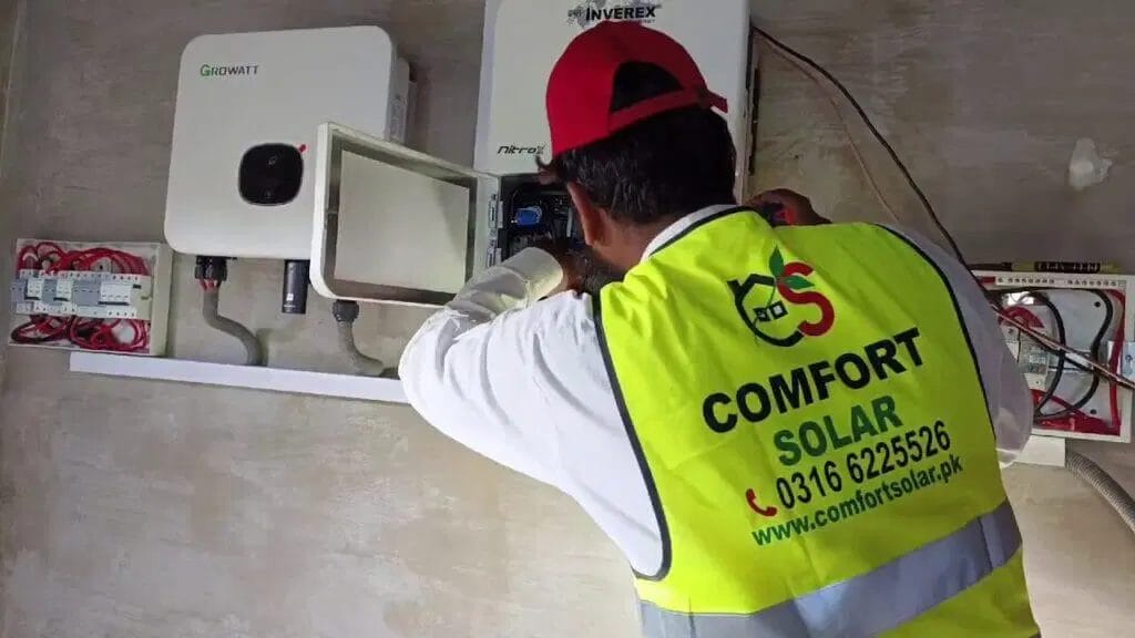 Comfort Solar technician installing solar inverter, Comfort Solar logo visible.