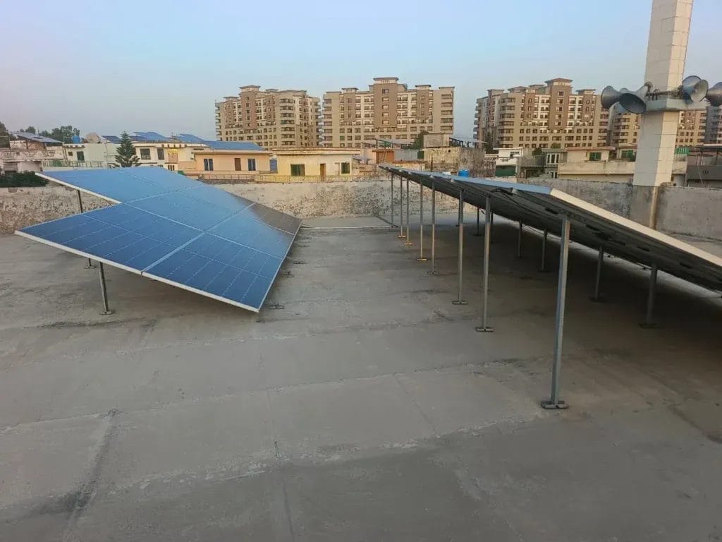 Solar panels installed on a rooftop with city buildings in background.